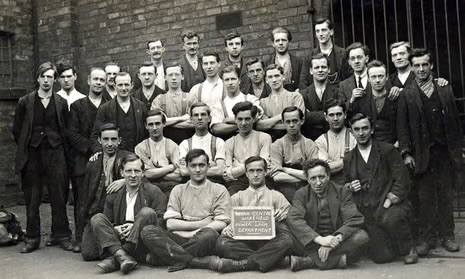 A 1917 photograph of a large group of men in civilian clothes outside a stone prison building on Dartmoor.